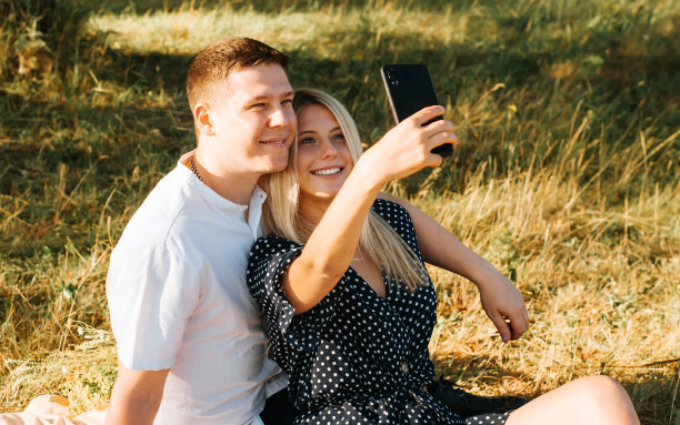 年轻的情侣们在野营时用手机拍下一张快乐的自拍，这张照片可以留念，也可以放到社交媒体上。美丽的爱情故事，户外约会。图片下载
