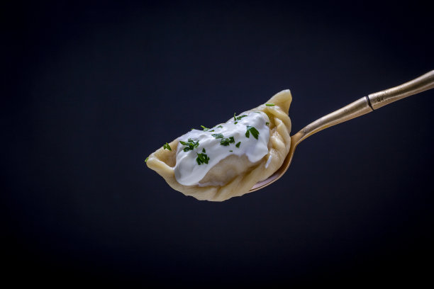 饺子配土豆泥或白软干酪，酸奶油和欧芹放在叉子上，黑色背景，结束图片下载