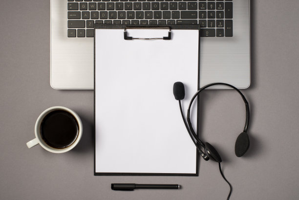 顶视图照片的笔记本电脑键盘黑色剪贴板文件夹与纸页耳机与麦克风笔和杯子的饮料在孤立的灰色背景与空白图片下载
