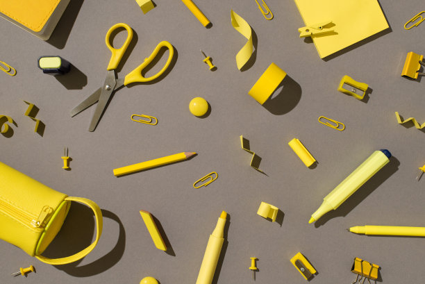 俯视图照片的黄色文具，学校用品，剪刀，毛笔，铅笔，便签，纸，胶带，磁铁，卷刀，橡皮，活页夹，别针，铅笔盒在孤立的灰色背景图片下载