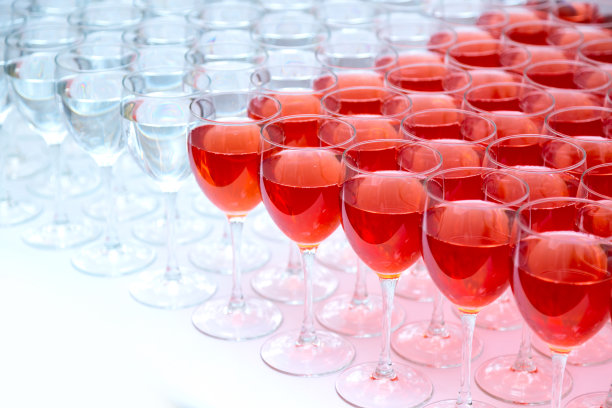 许多杯酒在一排。酒精的背景。图片下载