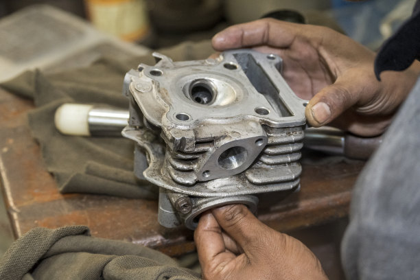 机修工修理摩托车的汽缸盖。图片下载