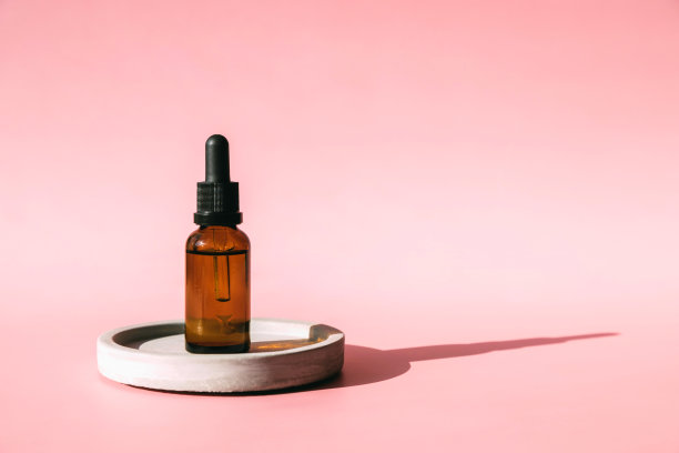 一罐用于面部皮肤护理的血清、维生素A酸、胶原蛋白或视黄醇放在混凝土基座上，背景是淡粉色。本空间图片下载