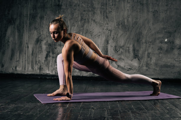 肌肉发达的年轻运动女性与完美美丽的身体穿着运动服做下面对狗在瑜伽垫锻炼。图片下载