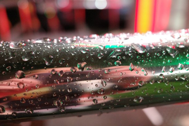 特写雨滴在金属栏杆上与光的反射。抽象的背景图片下载