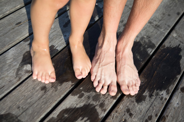 一个阳光明媚的夏日，沙滩上，一个孩子的双腿搭在木栈桥上。从以上观点。图片下载