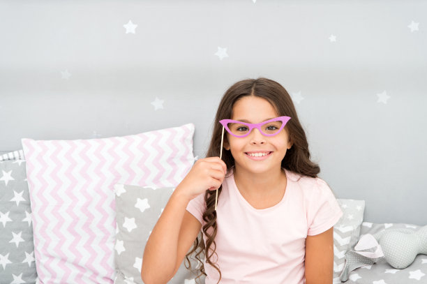 睡衣派对照相亭道具。小女孩愉快的摆着复古粉红眼镜派对属性。为聚会准备手工制作或购买的照片摊位道具。可印刷的照片亭道具睡衣派对图片下载