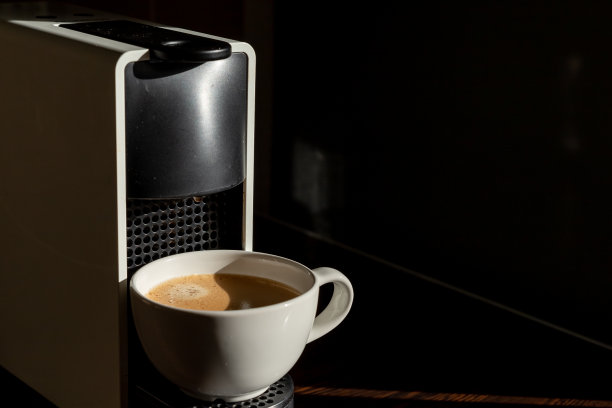 餐厅、咖啡馆、酒吧，白色的杯子放在咖啡机的格栅上，咖啡倒进杯子里。咖啡休息概念。新鲜的热饮放在白色的杯子里。本空间图片下载