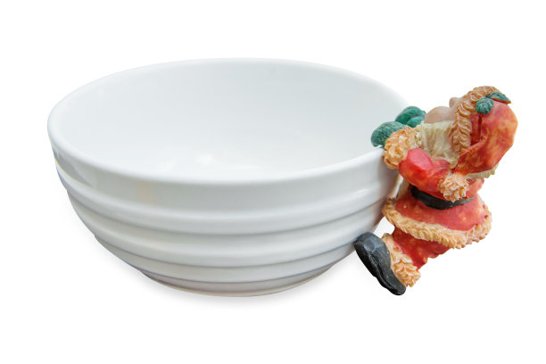 陶瓷娃娃挂在圣诞老人碗的边缘上，白色孤立。图片下载