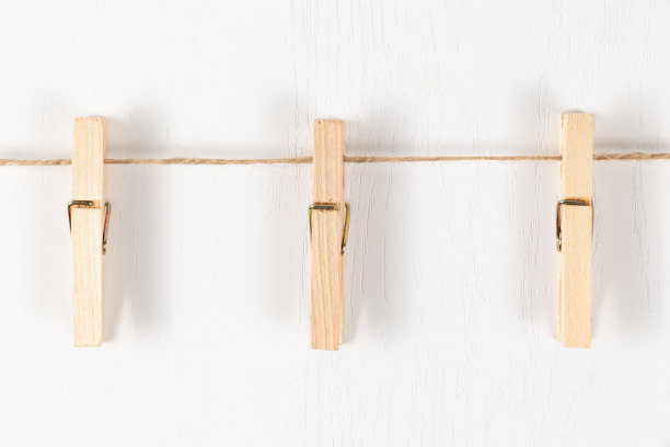 白色背景上的绳子上挂着三个带有金属弹簧的木衣夹图片下载
