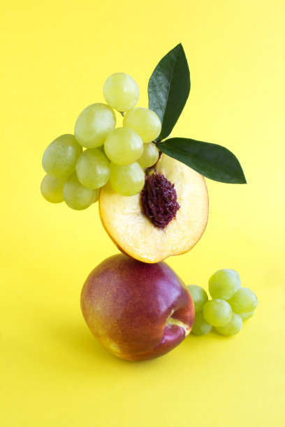 油桃和绿葡萄的平衡在黄色的背景中。特写镜头。图片下载