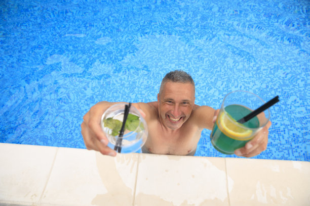 夏天的概念在泳池边的夏季派对，在游泳池的边缘，男人喝鸡尾酒和夏天的乐趣。图片下载