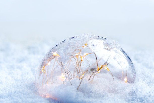 一个带着花环的透明球发出黄色的光芒，躺在雪地上图片下载