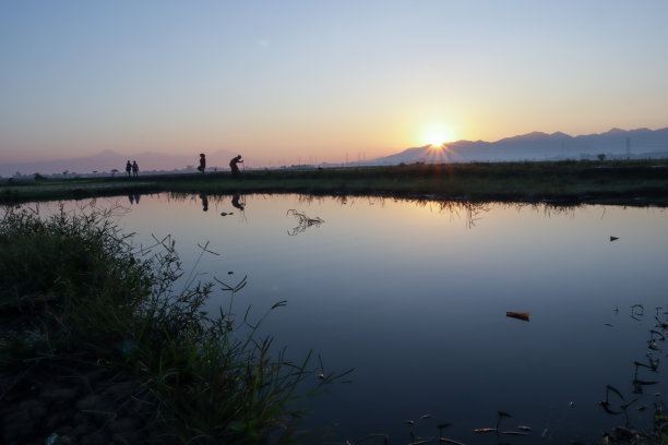 日出时池塘边的老妇人图片下载