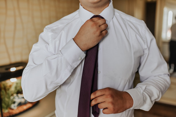 一个穿着白色衬衫的成年男子用手拉直了领带图片下载