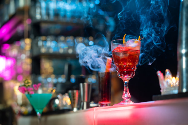 在夜总会吧台上用鸡尾酒杯加冰调制酒精饮料的酒保。图片下载