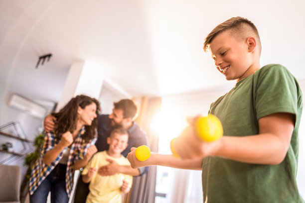 开心的小男孩在家人的支持下举重。图片下载