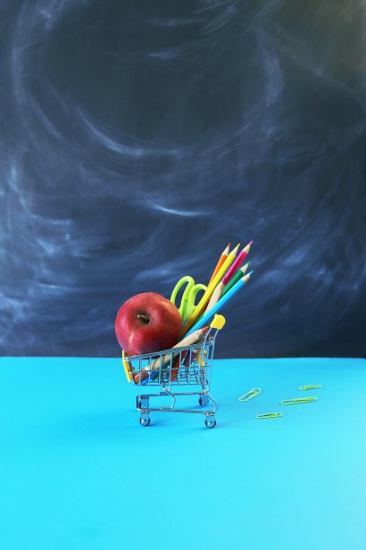 玩具手推车，文具和苹果在学校董事会的背景图片下载