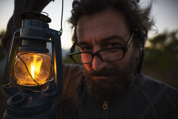 夕阳西下，灯笼的黄光映照在提灯人的脸上。图片下载