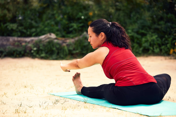 成年亚洲妇女做瑜伽在自然，做伸展和柔韧性练习，瑜伽班为成年妇女图片下载