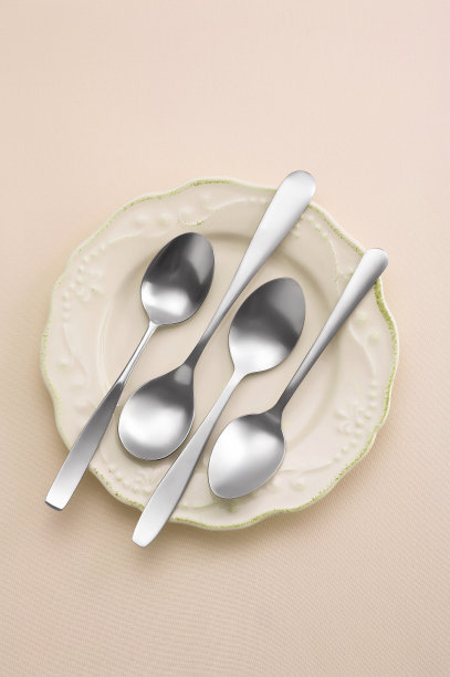 不锈钢勺子在陶瓷盘子上柔和的背景图片下载