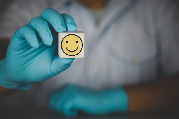 医生或科学家在实验室手持木块的笑脸图标。快乐服务的理念图片下载