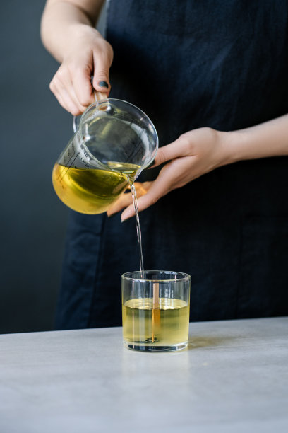 女孩把蜡倒入有灯芯的玻璃杯中。图片下载