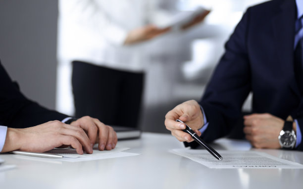 商务人士在会议或谈判中讨论合同，坐在一起，背景是一个不认识的女人，特写镜头。一群不知名的商人在一个现代化的办公室里。团队合作理念图片下载