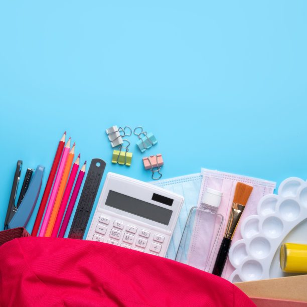 粉红色背包与文具在蓝色的桌子背景。图片下载