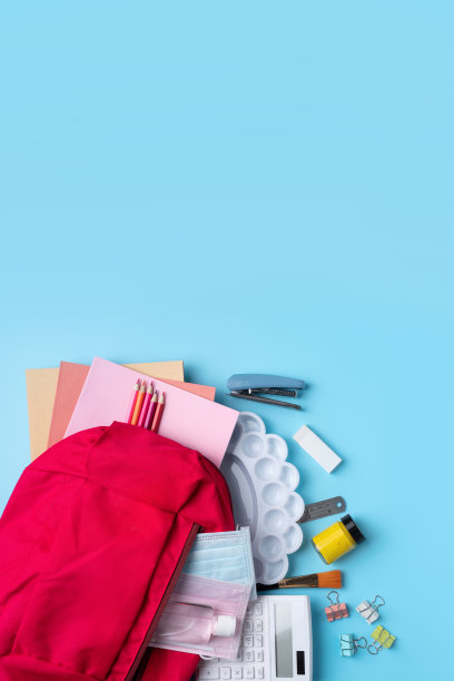 粉红色背包与文具在蓝色的桌子背景。图片下载