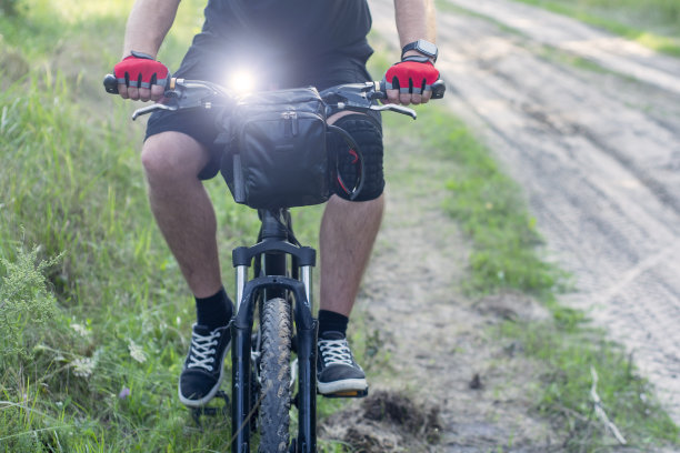 戴着手套骑山地车的人，车把上有包。图片下载