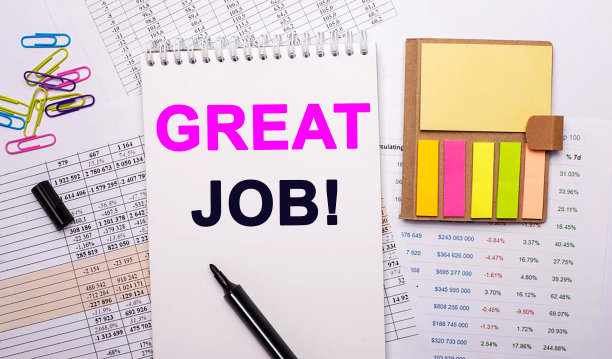 一个写着“伟大的工作”的记事本，一个马克笔，彩色回形针和明亮的贴纸放在图形的背景上。图片下载