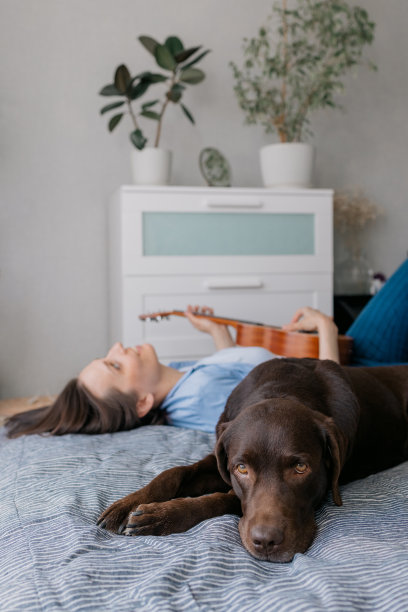 和她的狗一起弹吉他或尤克里里的女人图片下载