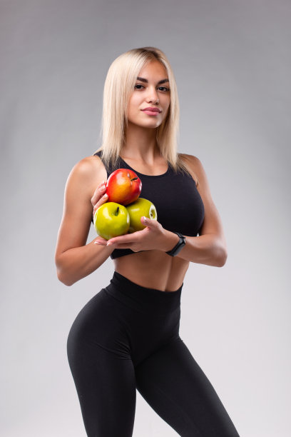 一个有着完美运动身体的女孩正拿着苹果。图片下载