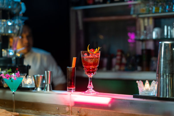 在夜总会吧台上用鸡尾酒杯加冰调制酒精饮料的酒保。图片下载