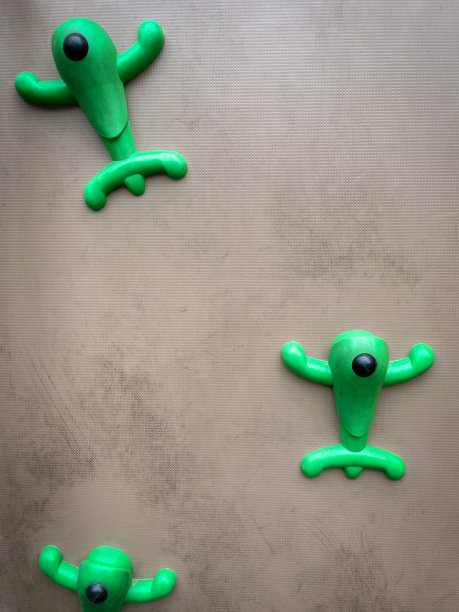 三个可爱的绿色攀爬手握在灰色粗糙的背景上图片下载