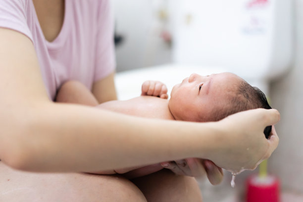 妈妈在她的怀里给刚出生的亚洲宝宝洗澡。爱与母亲节的概念。图片下载