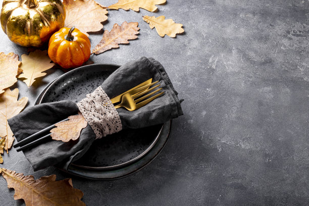 秋季餐桌设置概念。盘子，金色的餐具，南瓜和秋天的叶子在灰色的背景，照片与自由的文字空间图片下载