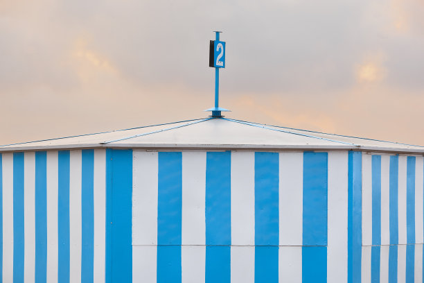 日落时的蓝色条纹海滩小屋。夏天的时间。旅游图片下载