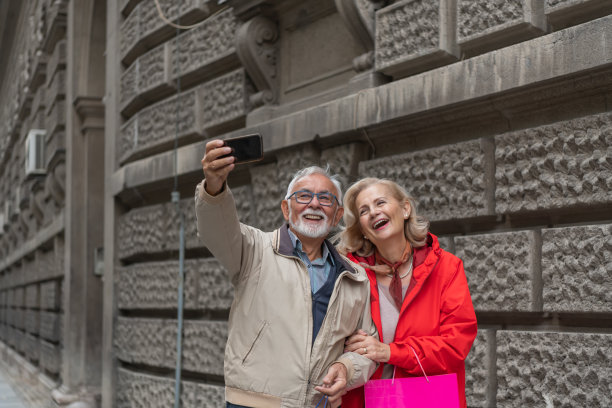 一对相爱的老夫妇在城区散步，享受一个秋天的下午并自拍照片。图片下载