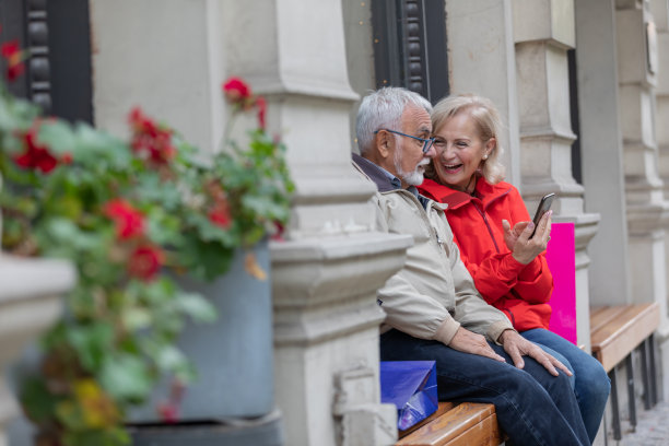 老夫妇在逛完购物中心后，坐在长凳上享受秋天的下午。图片下载