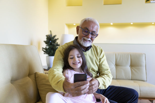 一位快乐的老人和他的孙女在家里微笑着自拍。图片下载