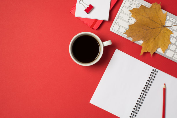 顶视图照片的黄色枫叶在白色键盘红色夹铅笔笔记本和咖啡在孤立的红色背景与copyspace图片下载