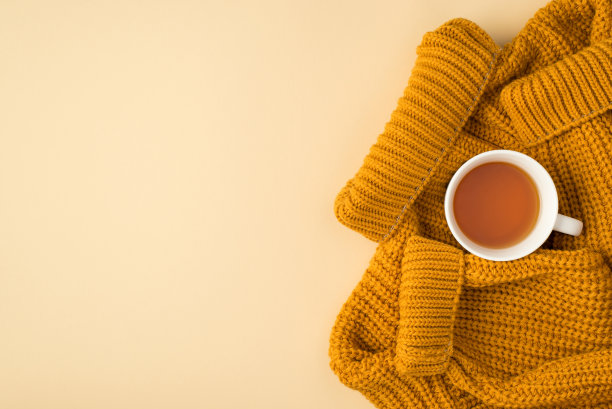 顶部视图照片黄色针织套头衫和茶杯在孤立的浅米色背景与copyspace图片下载