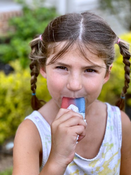 小女孩在炎热的夏天吃冷冻食品-库存照片图片下载