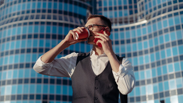 一个年轻人拿着智能手机在一个大办公楼的背景下图片下载