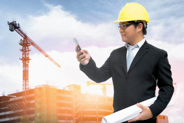 亚洲设计师工程师手里拿着蓝图，用智能手机与管理层沟通。图片下载