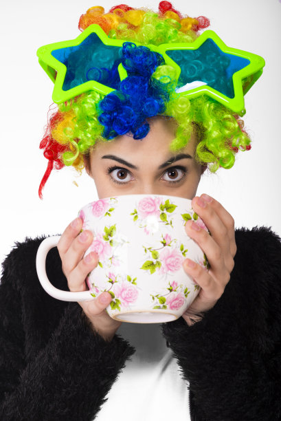 戴着彩色卷发假发、巨大眼镜、拿着巨大咖啡杯的有趣女孩图片下载