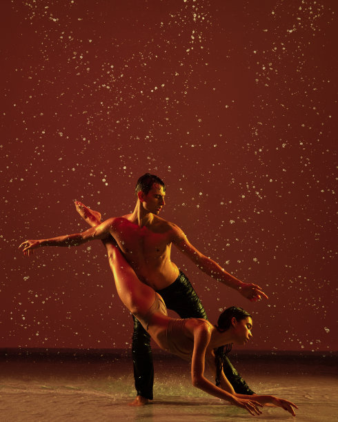 两个年轻的芭蕾舞者，男人和女人在红色背景下的雨中运动。爱，艺术，灵感概念。图片下载