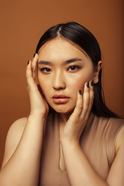 年轻漂亮的亚洲女性开朗的微笑，在温暖的棕色背景下，生活方式的人的概念图片下载